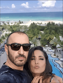 a man and a woman are posing for a picture in front of a swimming pool