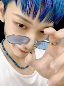 a person with blue hair is wearing sunglasses and a ring