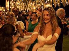 a woman in a wedding dress is dancing in a crowd of people .