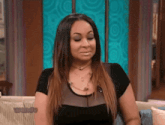 a woman is sitting on a couch wearing a black top and necklace .