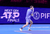 a man is playing tennis in front of a sign that says next gen finals