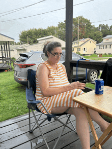 a woman is sitting at a table with a can of bud light