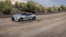 a silver sports car is driving down the road