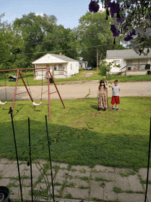 a boy and a girl stand in front of a swing set in a yard