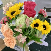 a bunch of flowers including sunflowers and roses in a box