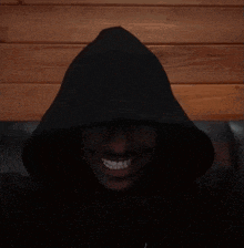 a person wearing a black hooded jacket is smiling