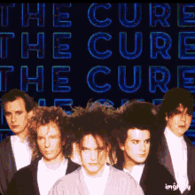 a group of men standing in front of the words the cure