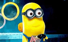 a cartoon minion wearing glasses and holding a bag of popcorn .