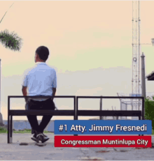 a man sits on a bench in front of a sign that says # 1 atty jimmy fresnedy congressman muntinutlupa city