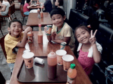 a group of children sit at a table with a tray of drinks including a can of sprite