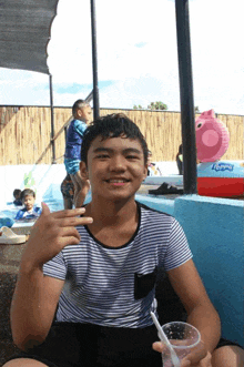 a boy holding a cup with a straw in front of a hoopla inflatable