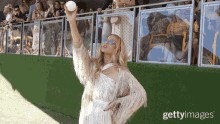 a woman in a white dress holds up a ball in front of a crowd of people with getty images written on the bottom