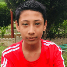 a boy wearing a red shirt with white stripes on the sleeves