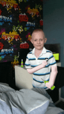 a boy in a striped shirt is holding a pair of scissors and a bottle of glue