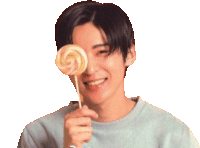 a young man is smiling and holding a lollipop in front of his eye .