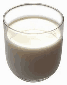 a glass of milk is sitting on a white surface .