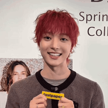 a young man with red hair holds a fastpaper card