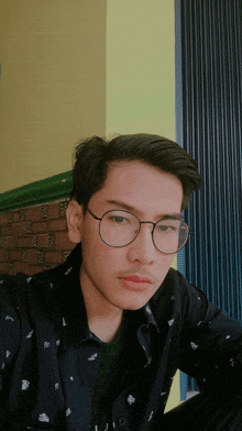 a young man wearing glasses and a black shirt is taking a selfie