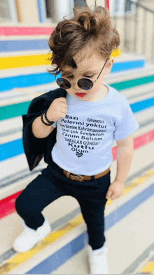 a little boy wearing sunglasses and a t-shirt that says " bazi "