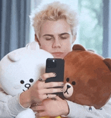 a man is taking a selfie with a teddy bear while holding a stuffed animal .