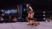 a woman in a blue top is wrestling another woman in a ring that says aew on it