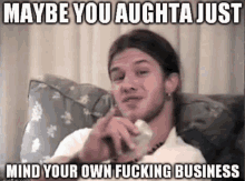 a man is sitting on a couch with a meme that says maybe you aughta just mind your own fucking business