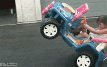 a little girl is playing with a toy car that has a jeep on it 's back .