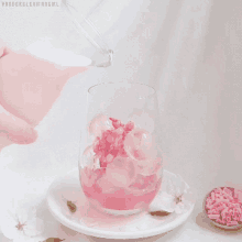 a person pouring pink liquid into a glass with ice cubes