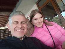 a man and a little girl are posing for a picture and the girl is wearing a pink jacket