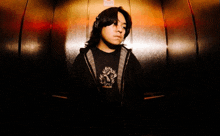 a young man wearing headphones and a black shirt with a lion on it stands in an elevator