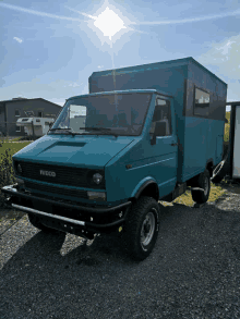 a blue iveco van is parked in a gravel area