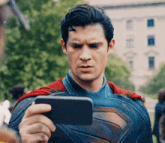 a man in a superman costume is taking a picture of himself with a cell phone