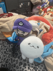 a stuffed character with a skull on his hat sits next to a white stuffed character