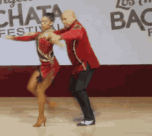 a man and a woman are dancing in front of a sign that says ' chata festival ' on it