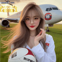 a girl holding a soccer ball in front of an airplane with the number 86 on the side