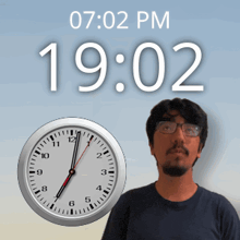 a man stands in front of a clock that reads 19:02 pm