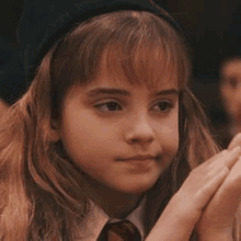 a close up of a young girl wearing a beret and a tie .