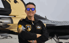 a man wearing sunglasses is standing in front of a fighter jet that says solo turk