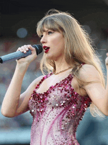 a woman singing into a microphone wearing a pink dress