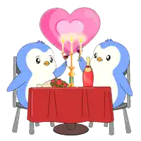 a couple of penguins sitting at a table with candles and a heart in the background