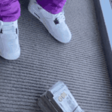 a person wearing white sneakers is standing next to a pile of money .