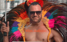 a shirtless man in a colorful feathered costume has the hashtag #belikebobo written on his chest