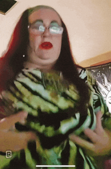 a woman with red hair and glasses is wearing a green and black dress