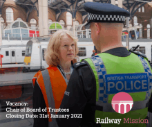 a man in a british transport police vest is talking to a woman