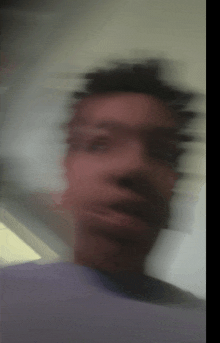 a blurry image of a man 's face with a purple shirt on