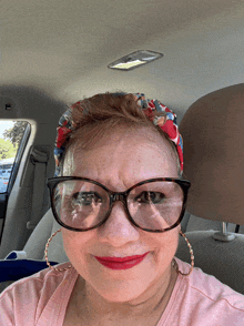 a woman wearing glasses and a headband is sitting in the back seat of a car