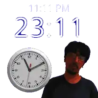 a man stands next to a clock that says 11:11 pm on it