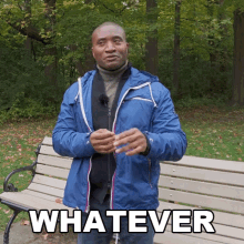 a man in a blue jacket is standing in front of a park bench with the word whatever written on it