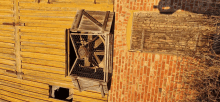 a wooden fan is attached to the side of an old brick building