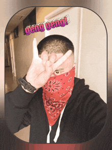 a man wearing a red bandana and a black hoodie is making a peace sign